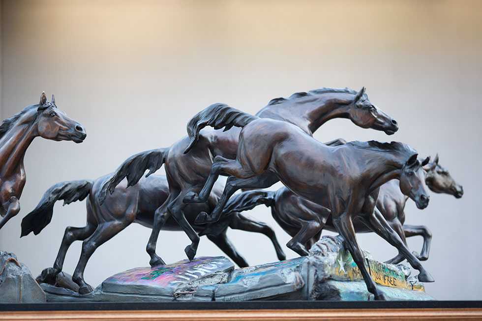 A sculpture of five horses leaping over the ruins of the Berlin Wall.